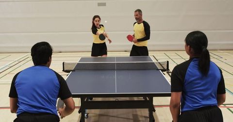 Energetic Doubles Table Tennis Match in Gymnasium