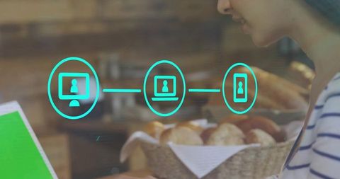 Woman Using Tablet in Cozy Bakery with Turquoise Network Icons Overlay and Warm Lighting