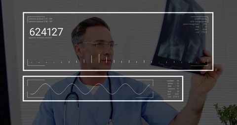 Mature male doctor in blue scrubs examining x-ray with augmented reality hud overlays