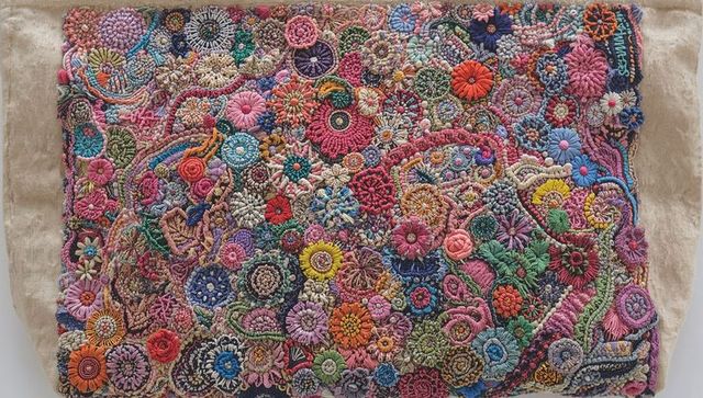 Hand-stitched floral embroidery featuring multicolor rosettes, knots and rich textured stitchwork
