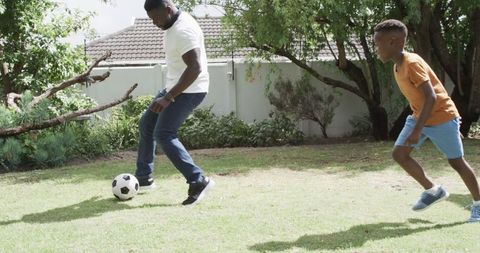 Father and Son Enjoying Soccer Game in Sunny Backyard