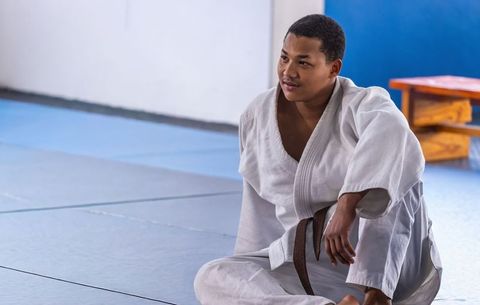 African american martial artist sitting on tatami wearing brown belt gi in dojo