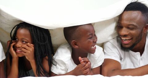 Joyful Family Enjoying Time Together under Blanket Indoors