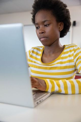 Focused Teenage Student Using Laptop in Classroom