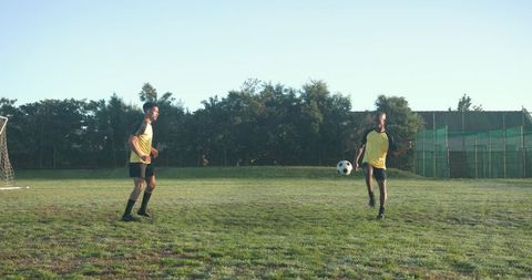 Soccer Players Practicing on Grassy Field at Dusk