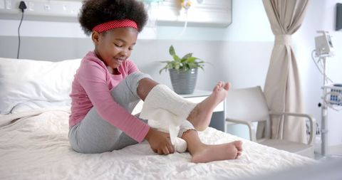 Young African American Girl Applying Bandage in Hospital Room