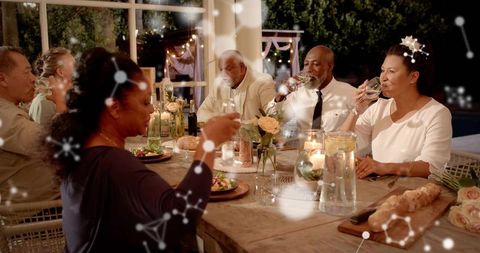 Elegant evening garden dinner party with adults raising wine glasses and candles