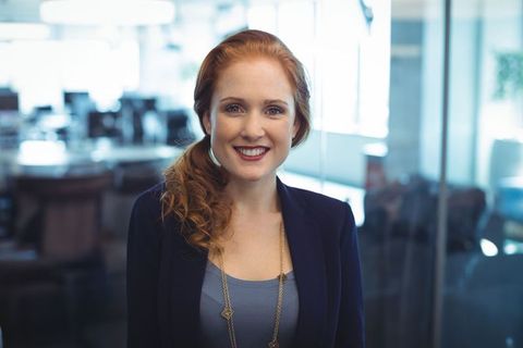 Confident Businesswoman Smiling in Modern Glass Office Setting