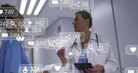 Female doctor reviewing tablet chart with nurse in hospital corridor, data overlays