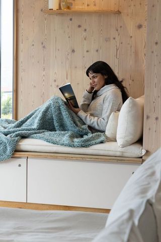Serene Woman Reading by Window in Cozy Blanket