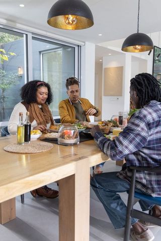 Friends Sharing Homemade Meal Around Light-Wood Dining Table in Modern Open-Plan Home