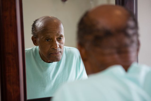 Mirror with reflection of concerned senior man in bathroom