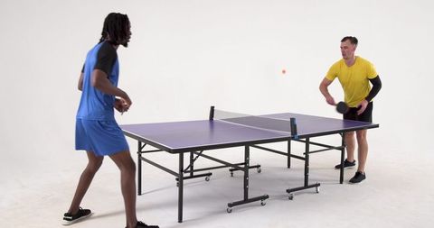 Diverse Male Friends Competing in Lively Table Tennis Match