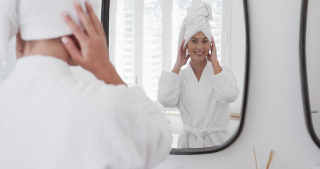 Woman in Bathrobe Looking in Bathroom Mirror Smiling with Towel Wrapped Hair - Download Free Stock Images Pikwizard.com