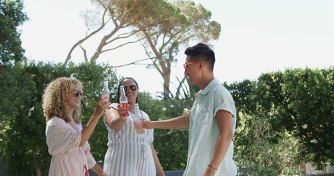 Joyful Friends Celebrating with Drinks Outdoors in Sunny Garden