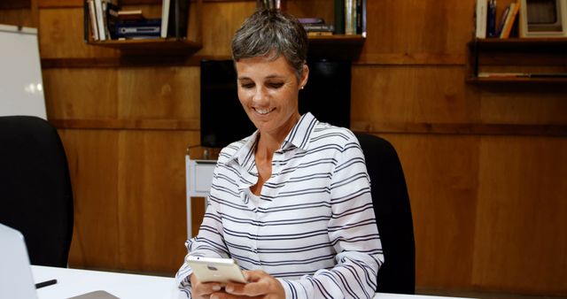 Smiling Businesswoman Checking Phone at Modern Office Desk - Download Free Stock Images Pikwizard.com