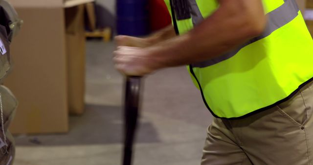 Warehouse worker moving items using hand operated pallet jack, highlighting manual labor in an industrial environment. Useful for concepts related to logistics, shipping, material handling, and warehouse safety procedures.