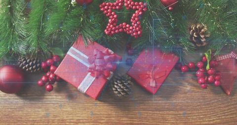 Arranging festive holiday gift cluster with pine, berries and ornaments on wooden tabletop