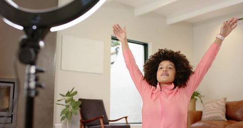 African american woman streaming wellness routine in bright living room with ring light