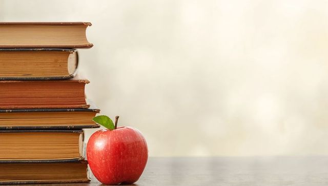 Stack of Vintage Books with Red Apple on Wooden Table