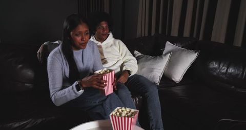 Couple enjoying movie night with popcorn on leather sofa