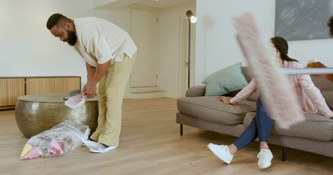 Happy Multiracial Family Enjoy Cleaning Living Room Together at Home