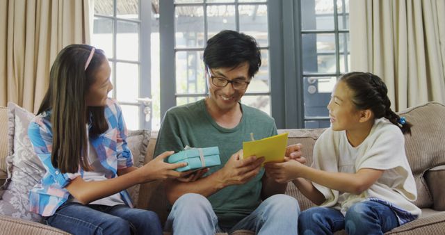 Father Receiving Gifts from Daughters on Couch in Living Room - Download Free Stock Images Pikwizard.com