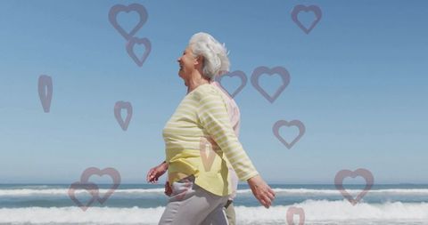Elderly couple walking on beach surrounded by hearts
