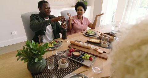 Couple Celebrating with Wine and Salad at Home Dining Table