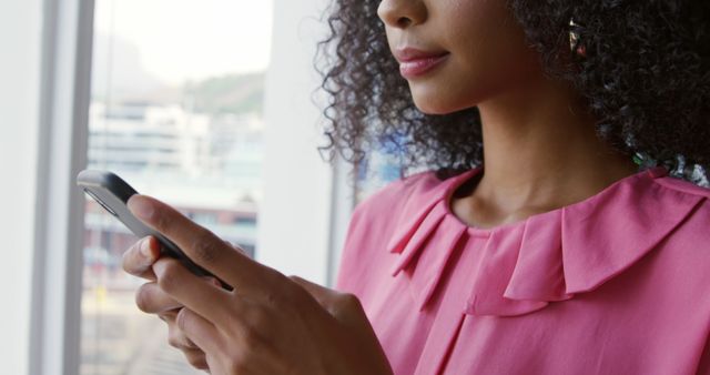 Young African American Woman Typing on Smartphone by Window - Download Free Stock Images Pikwizard.com