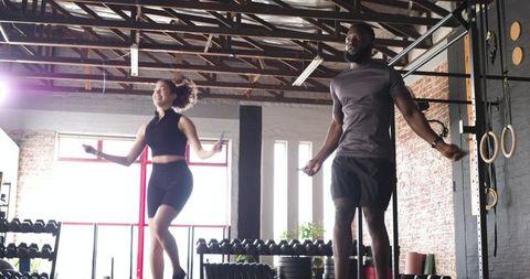 Diverse athletes jumping rope in modern gym environment
