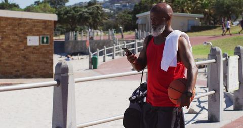 Senior Man Walking by Beach with Basketball