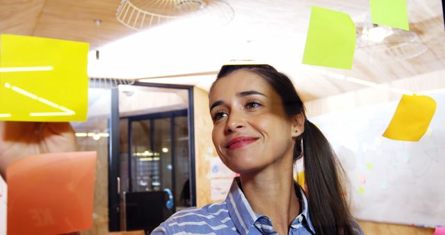 Smiling Woman in Office Solving Problems with Notes on Glass Wall - Download Free Stock Images Pikwizard.com