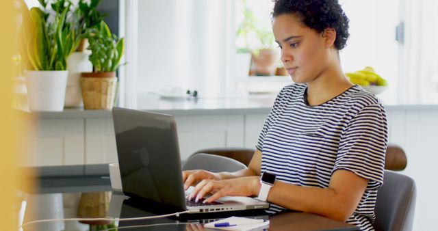 Focused Young Woman Working on Laptop at Home with Plants in Background - Download Free Stock Images Pikwizard.com