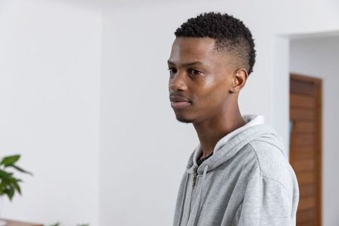 Young Man at Home in Casual Hoodie Ponders Thoughtfully