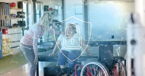 Rehab clinician assisting wheelchair user on therapy table with digital privacy shield