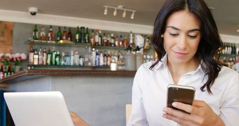 Young Woman Multitasking with Smartphone and Laptop in Bar - Download Free Stock Images Pikwizard.com