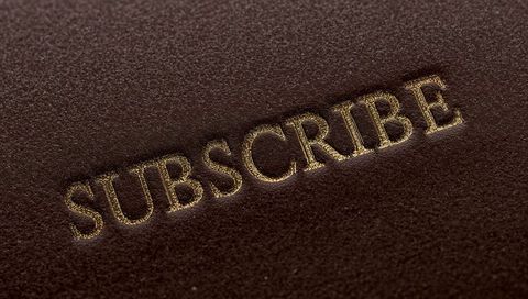 Embossed gold foil subscribe on brown leather texture closeup luxury call to action