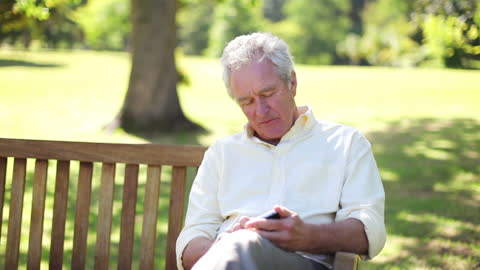 Senior Man Using Smartphone While Relaxing in Park