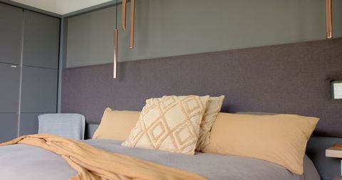 Modern relaxation in neutral toned bedroom with copper pendant lights