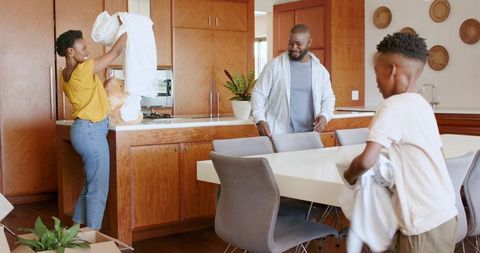 African american family unpacking and organizing midcentury kitchen while folding linens