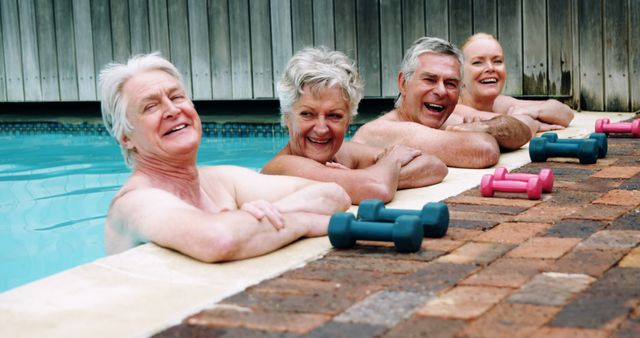 Senior Caucasian individuals are enjoying a water aerobics class in a swimming pool, with copy space. Their cheerful expressions and the presence of dumbbells suggest a focus on fitness and social interaction in their golden years.