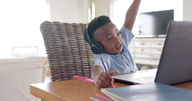 Happy african american boy with headphones learning online using laptop at home. Lifestyle, childhood, learning, online education, communication and domestic life, unaltered.