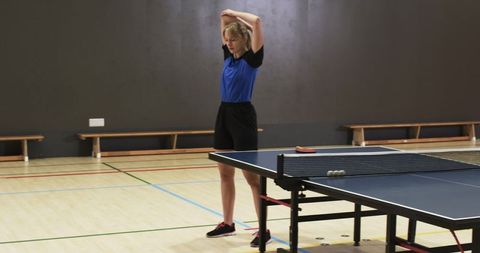 Woman Stretching Before Table Tennis Match in Gym