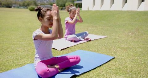 Two Biracial Girls Practicing Yoga Outdoors on Sunny Day