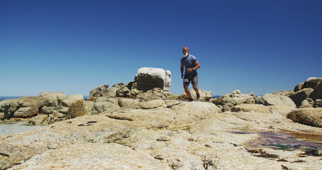 Man Hiking on Rocky Coastal Shoreline Under Clear Blue Sky - Download Free Stock Images Pikwizard.com