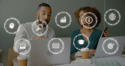 Man pointing and woman holding phone collaborating with laptops and floating digital icons