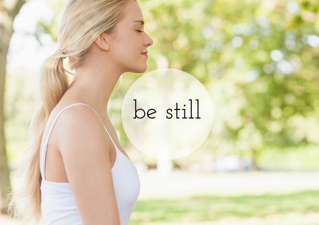 Woman meditating outdoors in sunny park with the words 'be still'. Ideal for marketing materials related to wellness, meditation, mindfulness, yoga practices, health and wellness blogs, relaxation content, stress relief strategies, and personal growth promotion.