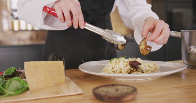 Chef Garnishing Pasta with Grilled Mushrooms in Modern Kitchen - Download Free Stock Images Pikwizard.com