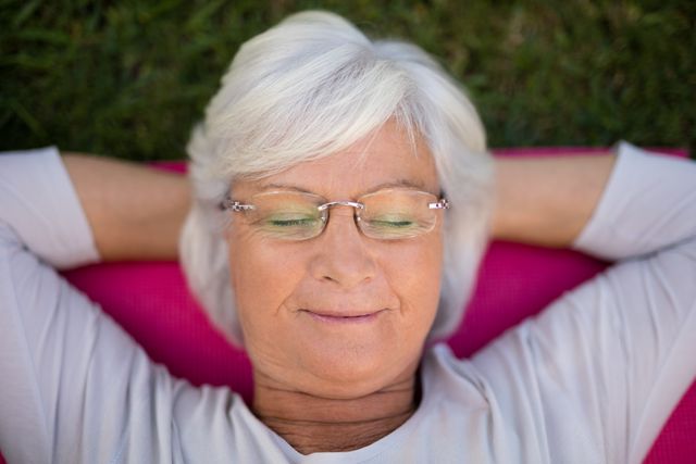 Senior Woman Relaxing on Exercise Mat in Park - Download Free Stock Photos Pikwizard.com